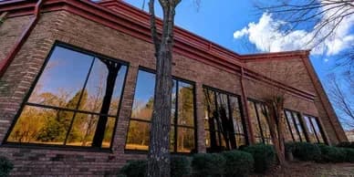 Brick commercial building in Edmonton with dark exterior window film across its storefront glazing